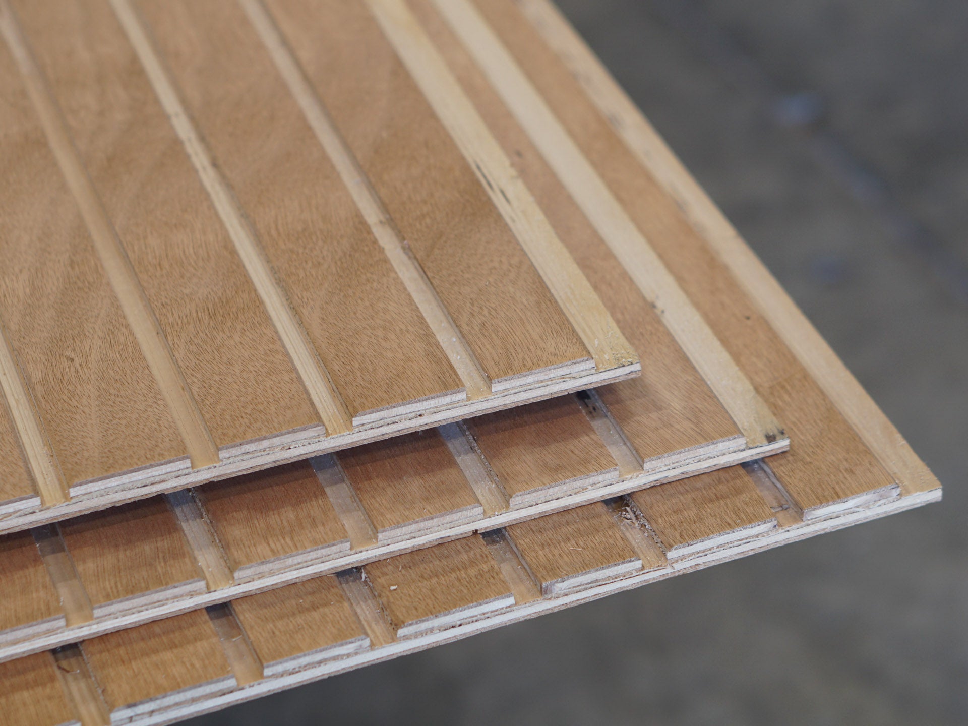 Closeup of a stack of three sheets of Wideline patterned plywood consisting of a 3/8" groove, 2" on center, commonly used as siding and paneling on Eichler homes and other mid-century modern design