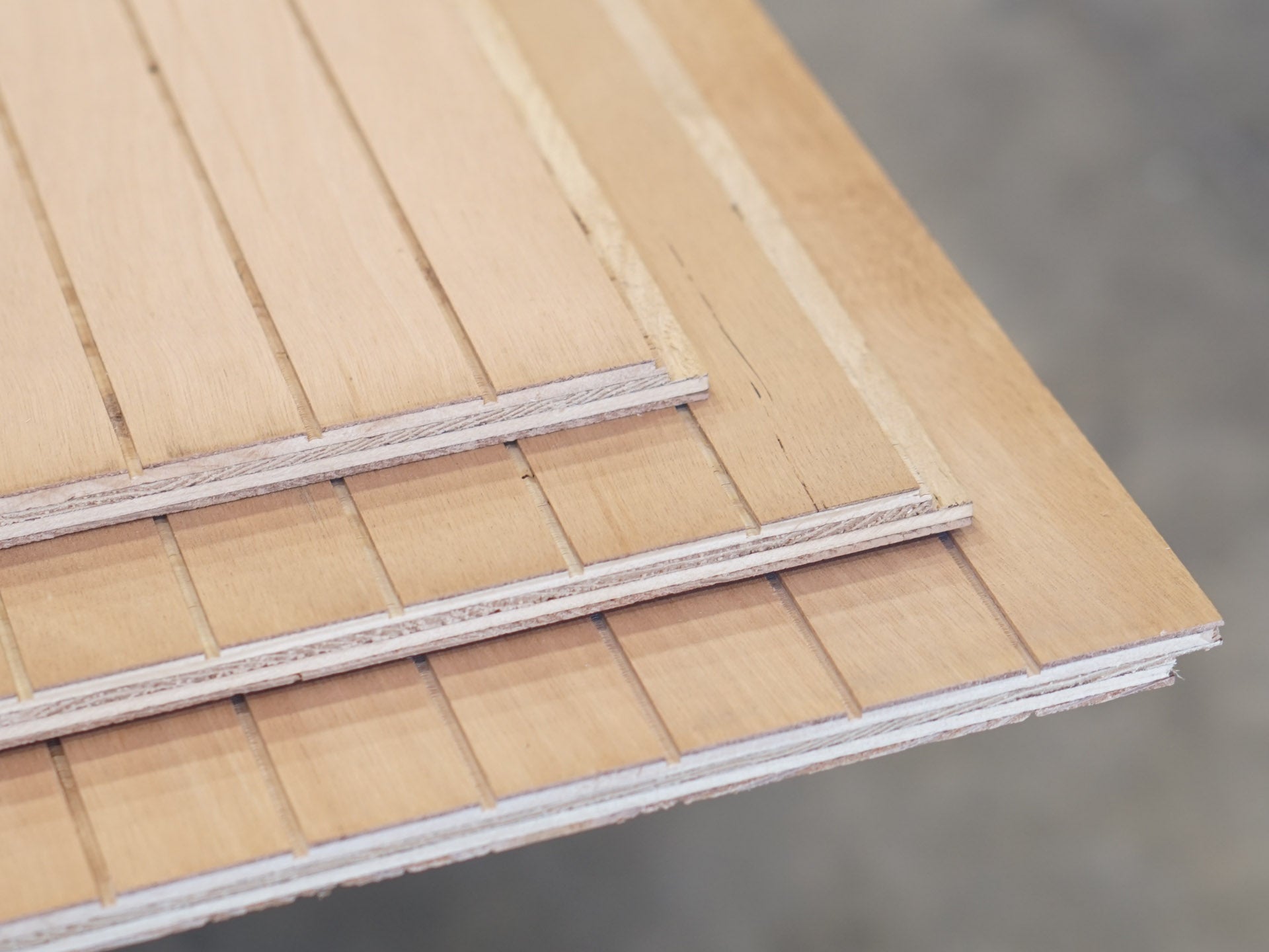 Closeup of three sheets of Thinline patterned plywood consisting of a 1/8” grooves, 1⅝” on center, commonly used as siding and paneling on Eichler homes and other mid-century modern design